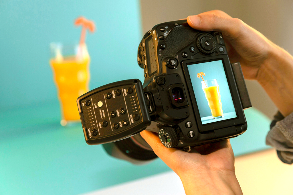 A professional camera capturing a clear image of a glass of orange juice with a decorative umbrella, representing Miami's vibrant and creative business culture.