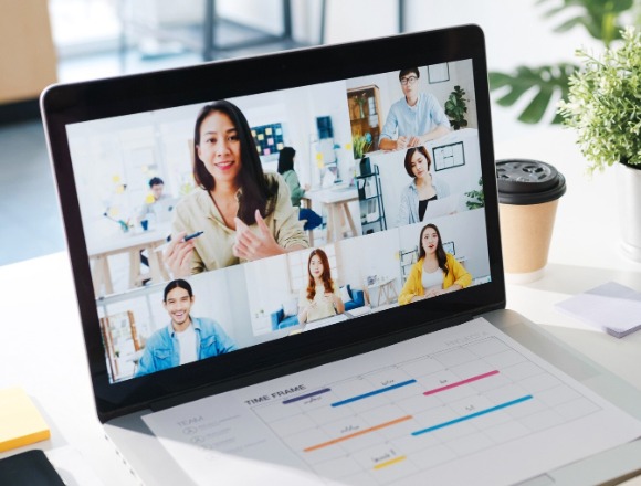 A laptop displaying a virtual meeting with six participants and a project timeline chart, symbolizing remote collaboration for website development projects in Miami, Florida.